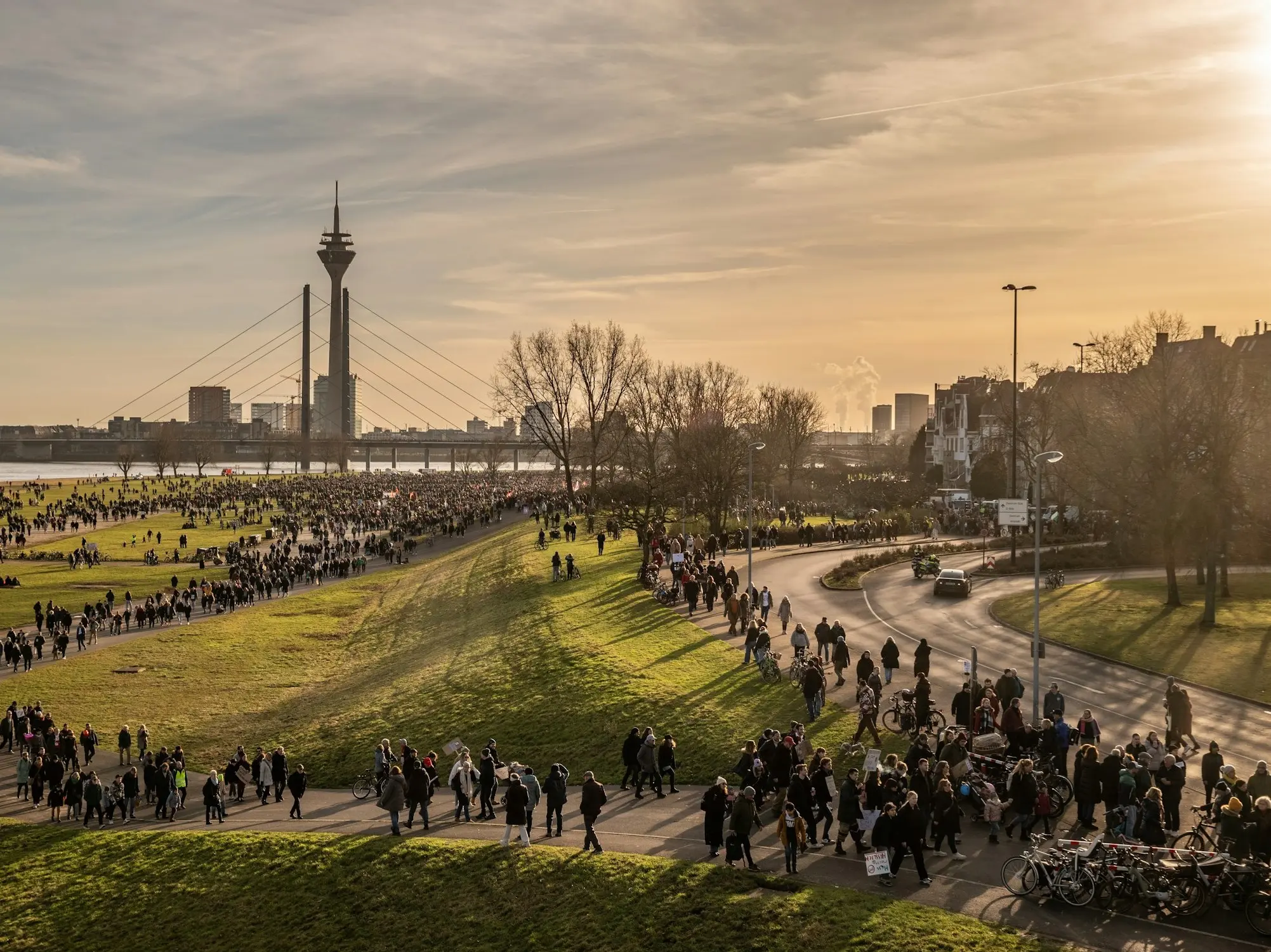 Menschen in Düsseldorf laufen am Rhein entlang auf dem Weg zu einer Demonstration