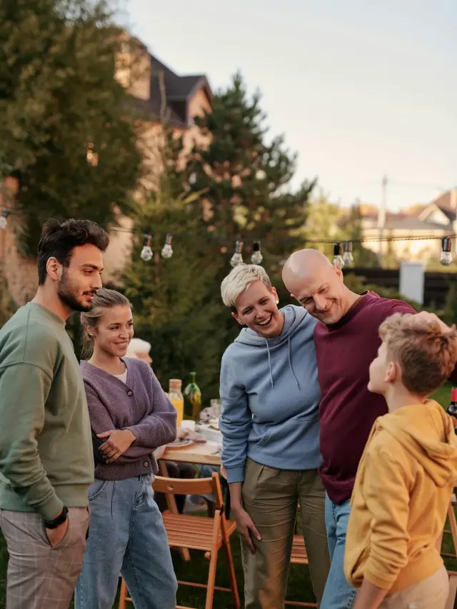 Fünf Nachbarn unterhalten sich bei einer Gartenparty und lachen