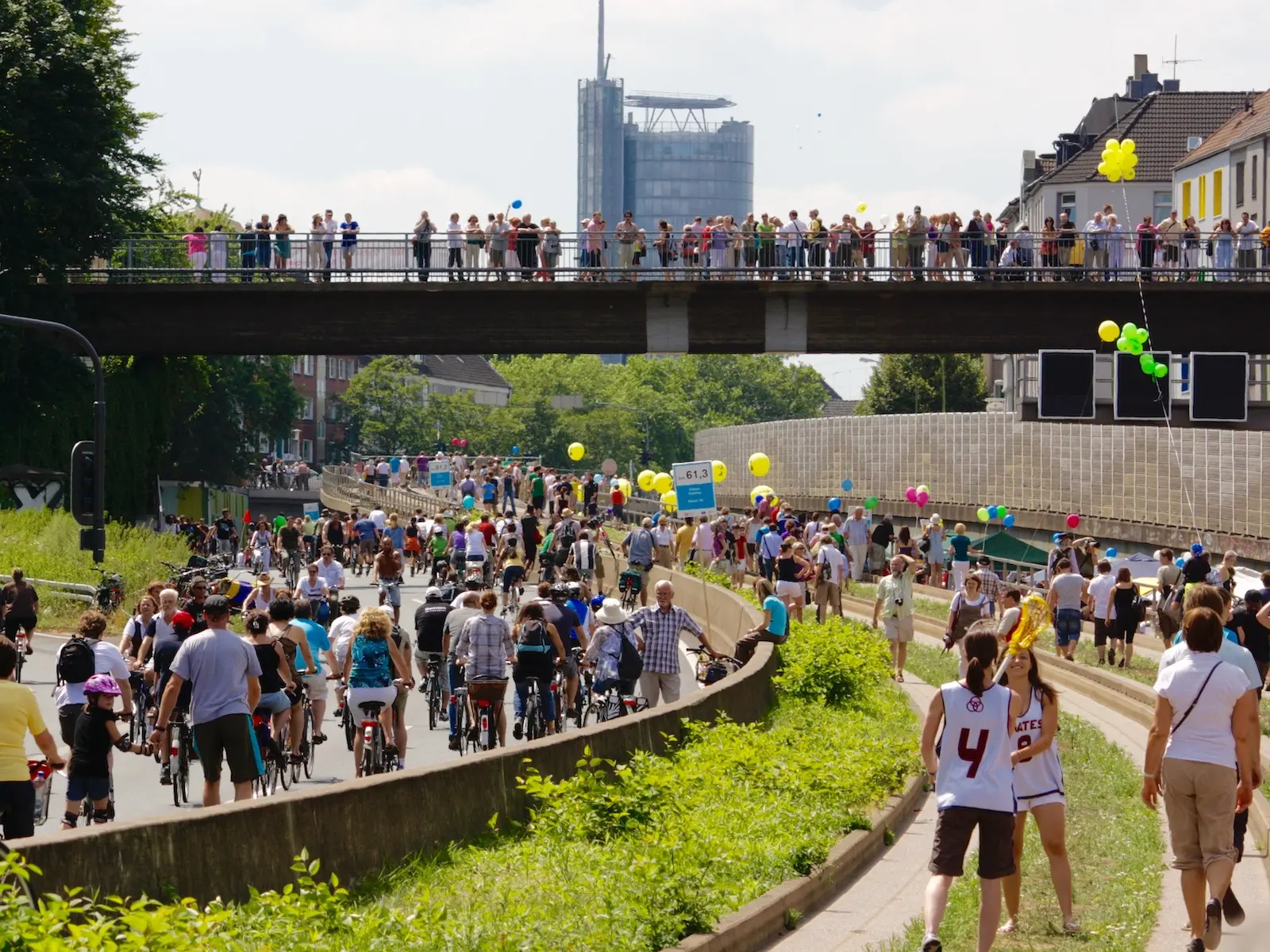 Menschen in Essen sind zu Fuß und Fahrrad unterwegs auf einer Demonstration, überall sind bunte Luftballons zu sehen